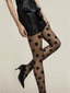 Transparente Strumpfhose mit großen schwarzen Punkten, elegant kombiniert mit kurzem Rock und Pumps.