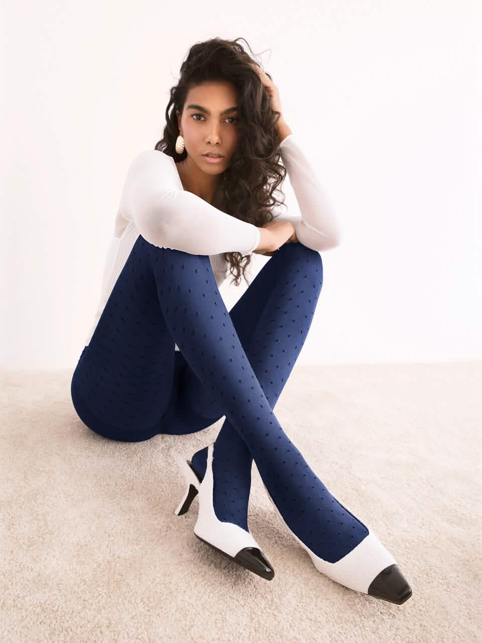 Dame mit blauer Strumpfhose mit Punkten sitzt auf Teppich, elegante Mode, Nylonstrumpfhose 主圖