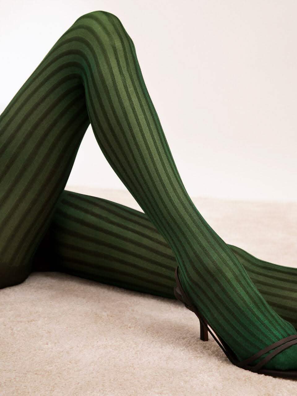 Grün gestreifte Strumpfhose für Damen, elegant, blickdicht auf hellem Teppichboden