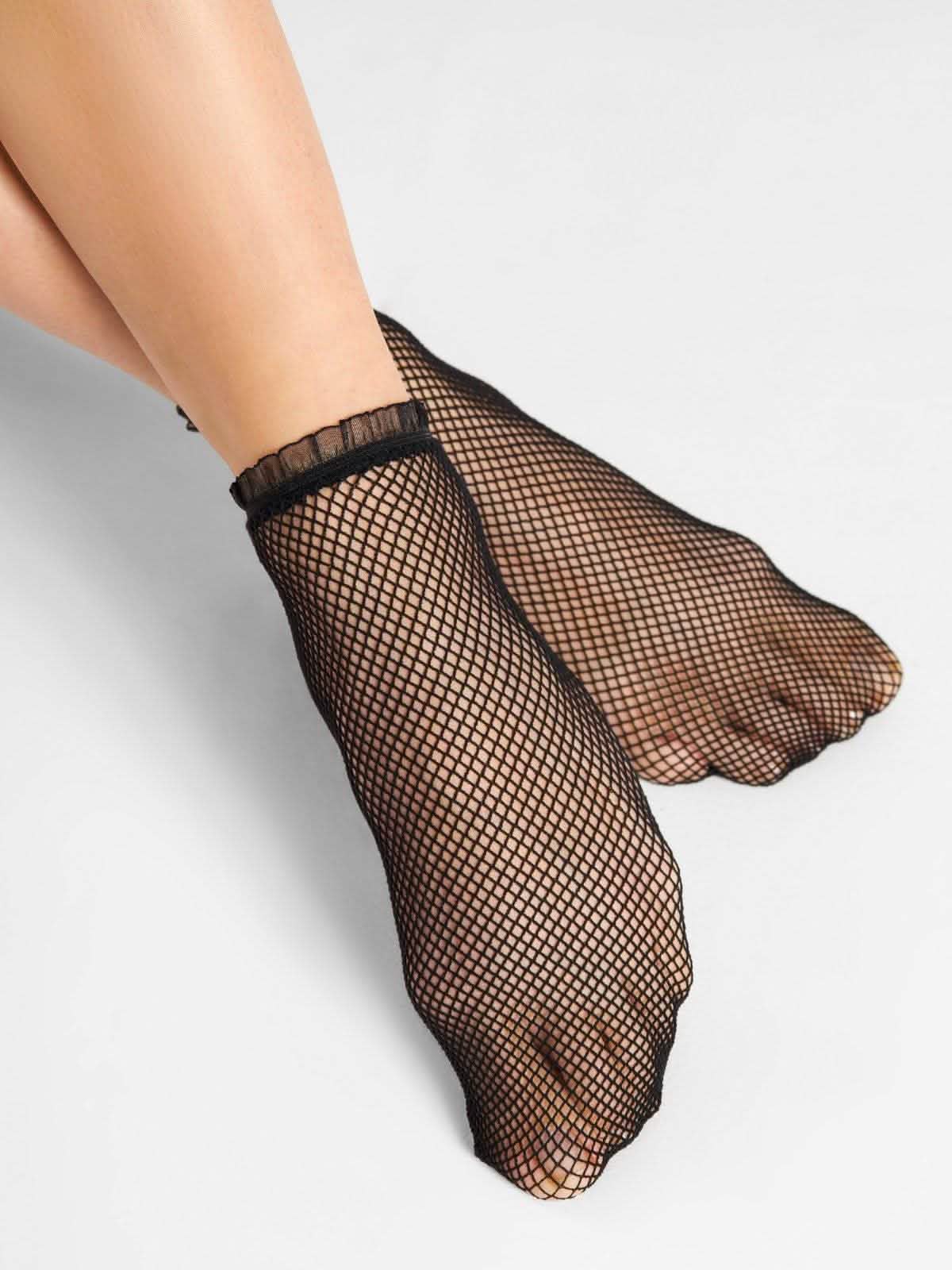 Schwarze Netzsocken aus Nylon an weiblichen Füßen, elegant und modisch auf weißem Hintergrund Hovedbillede