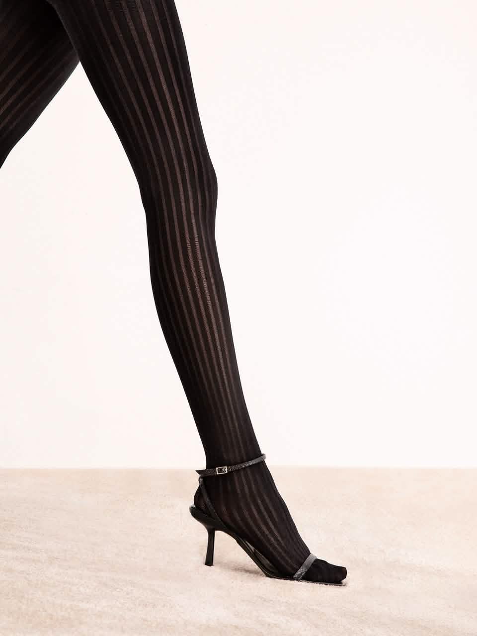 Schwarze Strumpfhose mit Streifenmuster und High Heels auf hellem Teppich