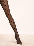 Damenbein in schwarzer Strumpfhose mit geometrischem Mesh-Muster und High Heels auf hellem Boden.