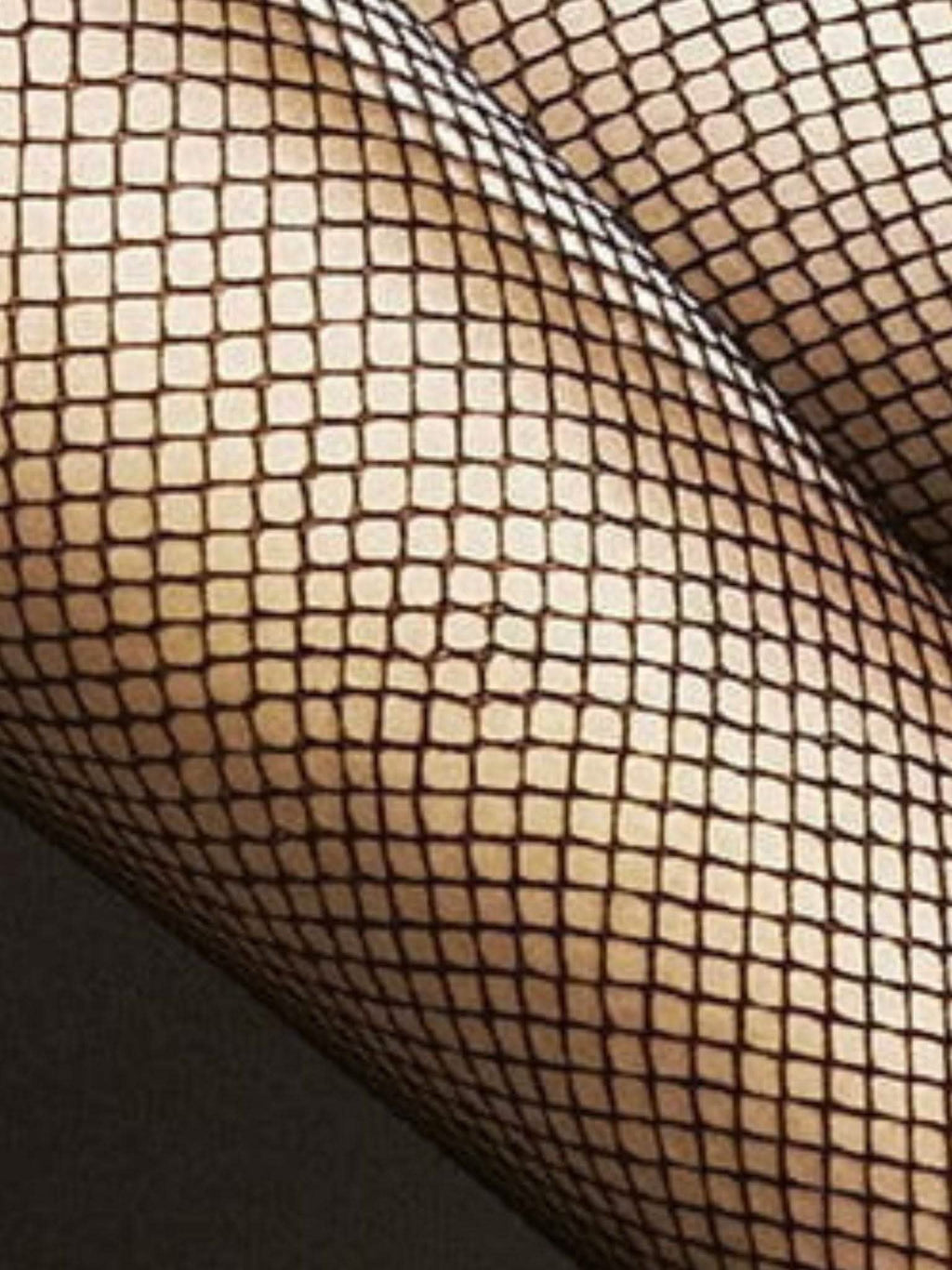 Nahaufnahme von Beinen in schwarzer Netzstrumpfhose, elegantes Fischgrätmuster